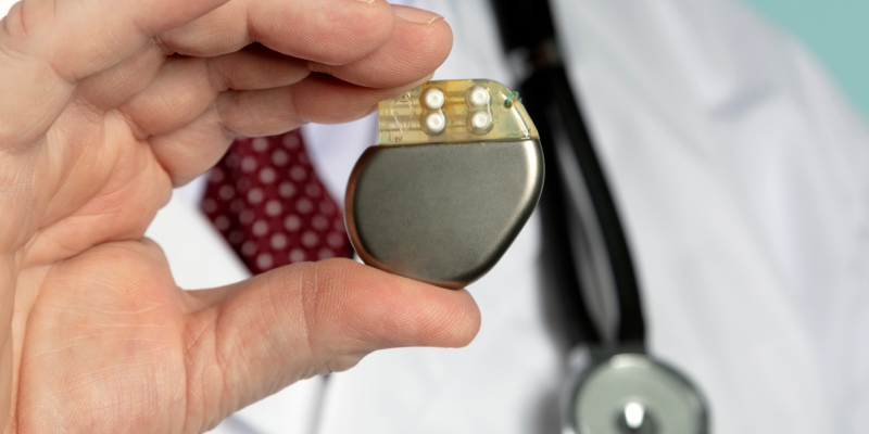 An image of a health professional holding a pacemaker illustrates the vital role pacemakers play in regulating and saving the heartbeat.